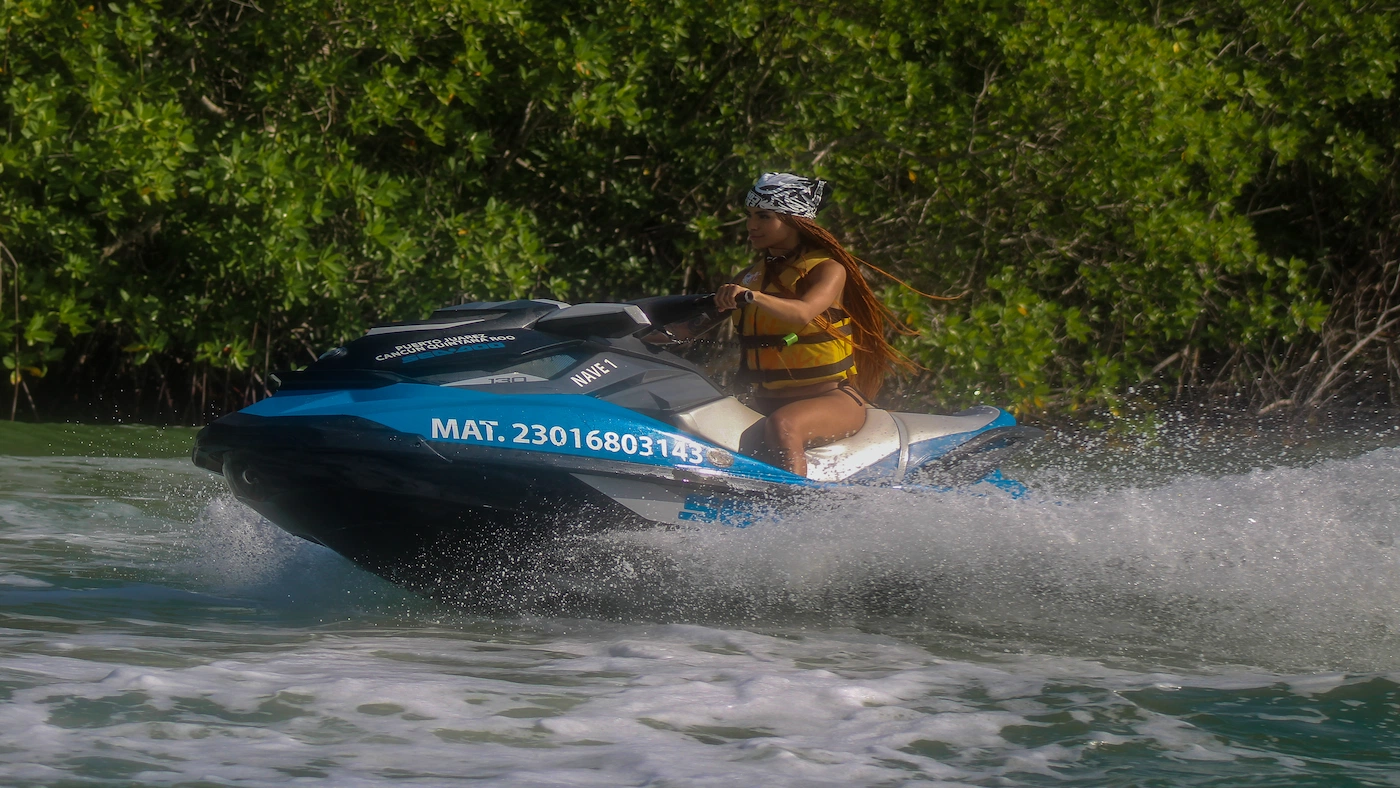 A pretty girl rides a rented jet ski through the mangrove canals in Cancun.
