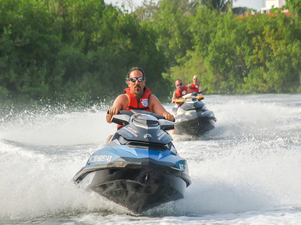 Three friends ride rented jet skis through the mangrove canals at full speed.